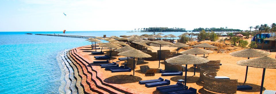 Et eksotisk strandanlegg i El Gouna med solsenger og parasoller langs en klar blå kyst.