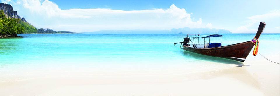 En tradisjonell langhalebåt står ved en vakker tropisk strand med krystallklart vann og blå himmel.