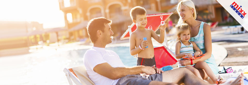 En familie koser seg i solen ved et basseng. Barna leker med leker mens foreldrene slapper av.
