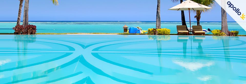 Bilde av en fristende svømmebasseng ved stranden med palmer og solsenger under en parasoll.