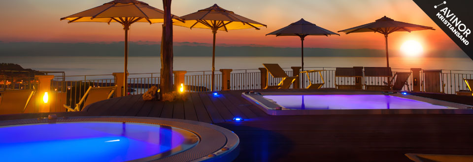 Bilde av en terrasse med svømmebasseng og parasoller i solnedgangen med utsikt over havet.