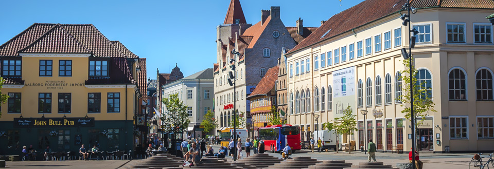 Nytorv og Boulevarden i Aalborg med  fargerike bygninger, gående mennesker og en rød buss.