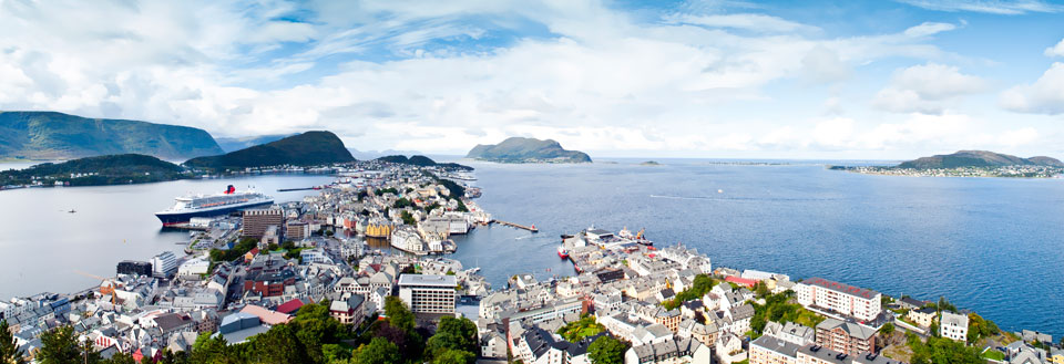 Panoramautsikt over en kystby med fargerike hus, et cruiseskip i havnen og omliggende fjell.
