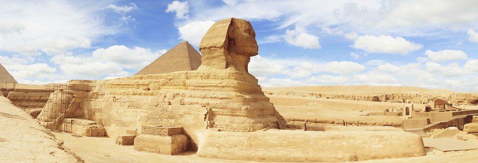 Bildet fremviser Sfinksen og pyramidene i Giza mot en klar himmel i Egypten.