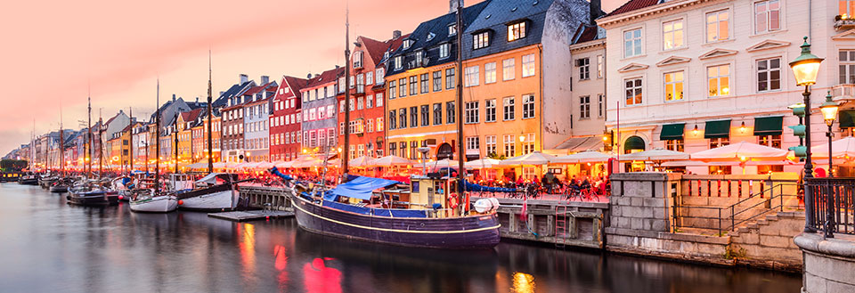 Bilde av Nyhavn i København i skumringen med fargerike bygninger og båter langs kanalen.