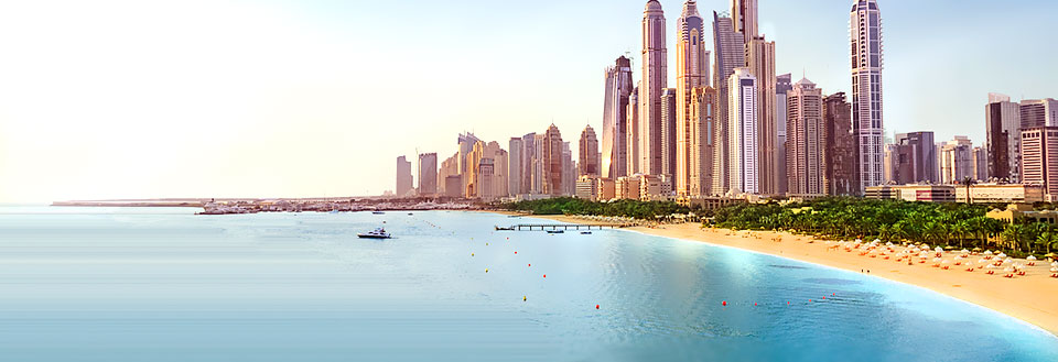 Et panorama av en moderne kystby med høyhus og en sandstrand langs et klart blått hav.