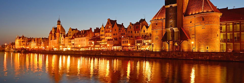 Kveldsbilde av Gdansk ved elven, lysene fra bygningene reflekteres i vannet.
