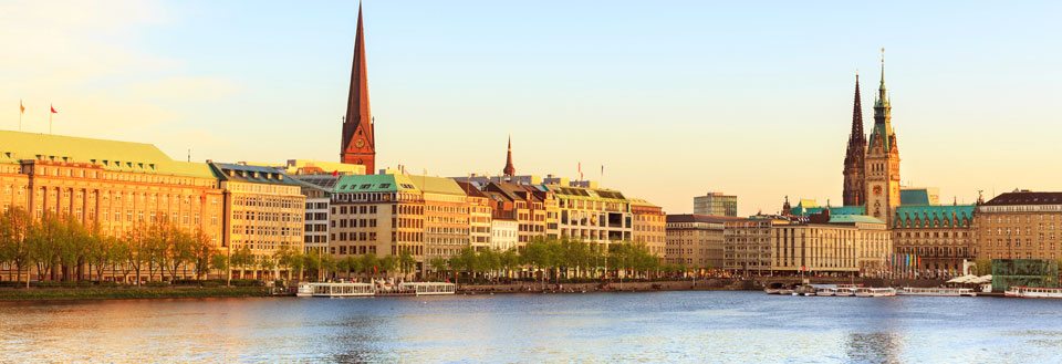 Panoramautsikt over en elvebredd med en blanding av moderne bygninger og historiske spir.