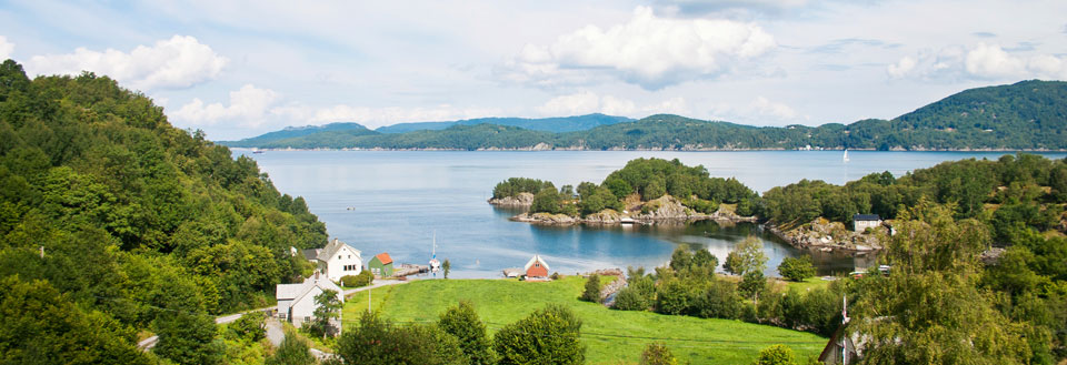 Idyllisk norsk fjord med hus, grønne områder og små øyer.