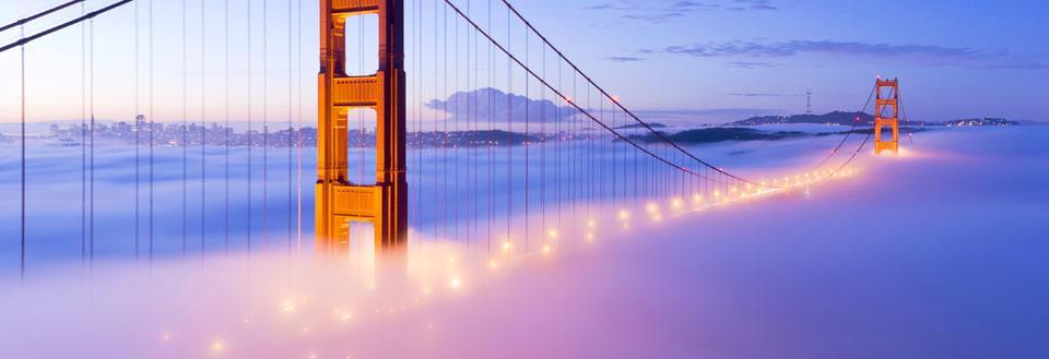 Golden Gate Bridge i skumringen, opplyst og svevende over en tett tåke.