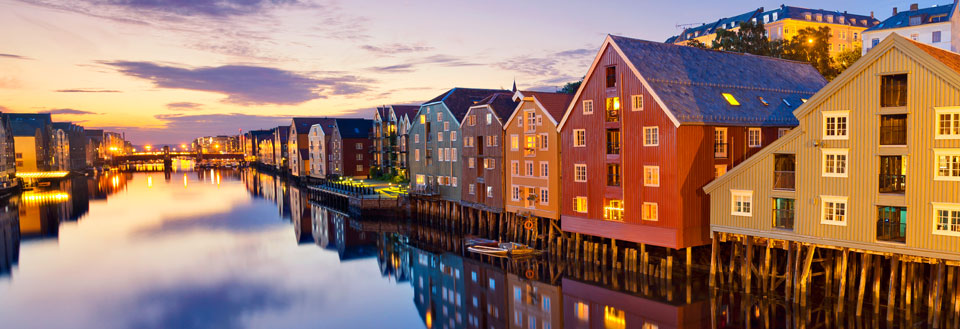 Fargerike trehus reflekterer i vannet i skumringstimen i Trondheim.
