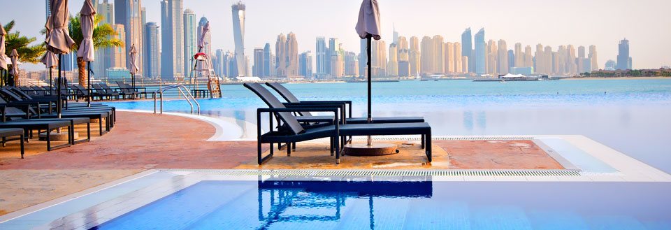 Luksuriøs svømmebasseng foran en moderne bysilhuett med imponerende skyskrapere i Dubai.