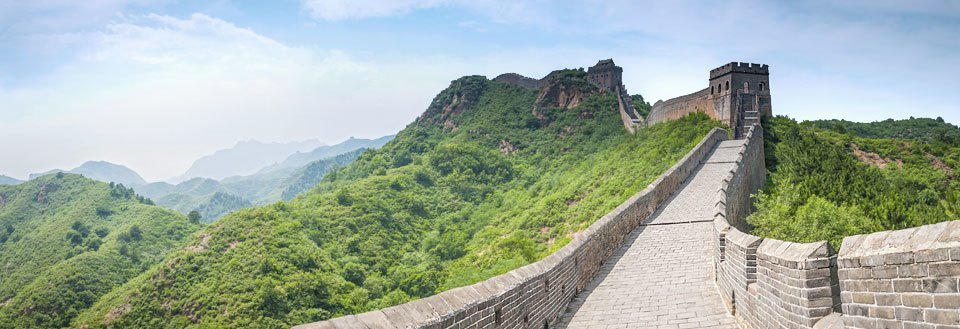 Panorama av Den kinesiske mur som slynger seg gjennom et frodig landskap.