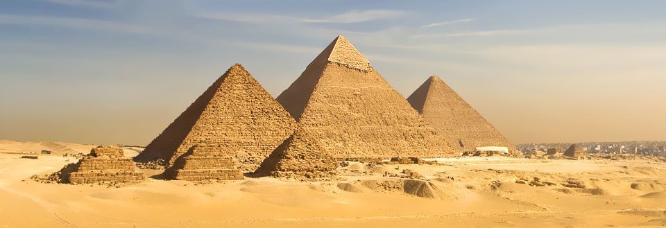 De majestetiske pyramidene i Giza mot en klar himmel, omringet av ørken.
