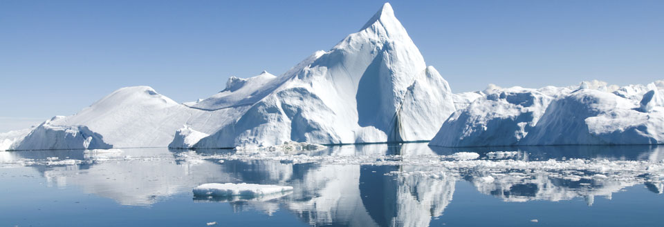 Majestetisk isfjell i et fredelig polarhav, med refleksjoner i det klare vannet.