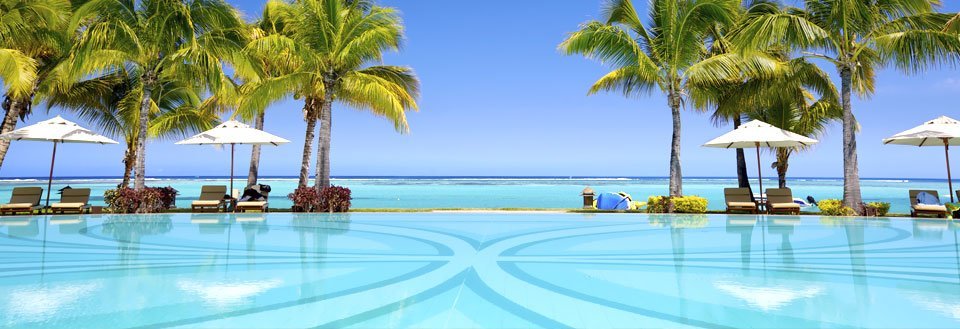 Tropisk feriested med svømmebasseng og palmer mot en klar blå himmel.