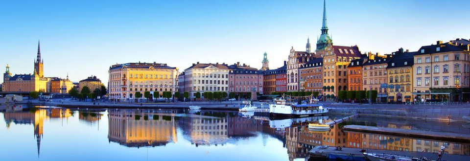 Stockholm  i skumringen, med speilbilder av fargerike bygninger og båter.