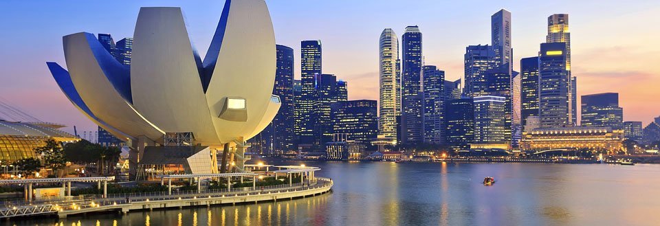 Et panoramabilde av Singapore i skumringen, med Marina Bay Sands og en lotusformet bygning.