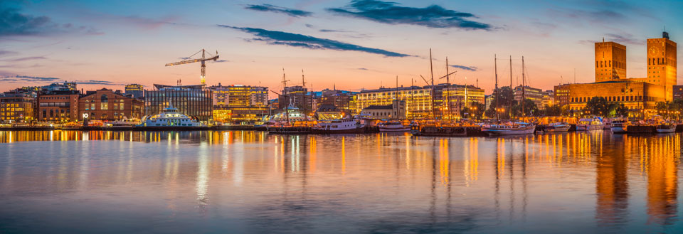 Panoramautsikt over Rygge ved skumring med opplyste bygninger og refleksjon i vannet.