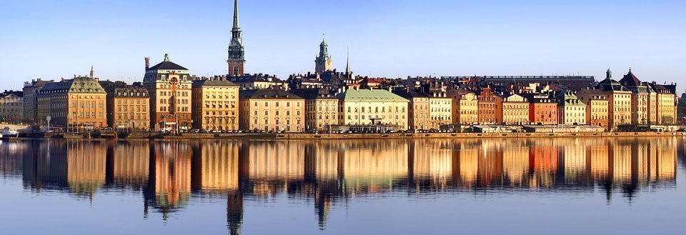 Panoramautsikt over Stockholm bygninger speilet i vannet ved solnedgang.