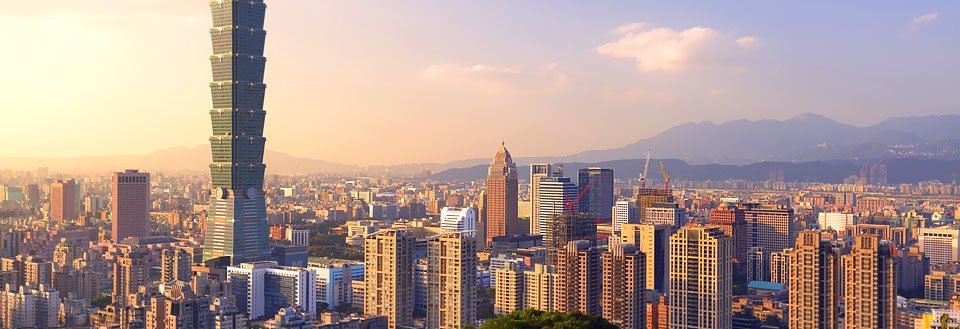 Taipei i solnedgang med skyskrapere og et dominerende høyt tårn.